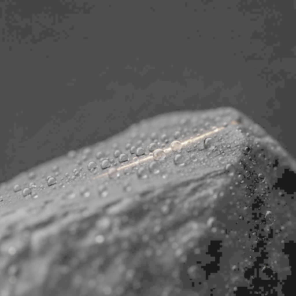 Wassertropfen auf einer hellgrauen Mineraloberfläche im Tageslicht