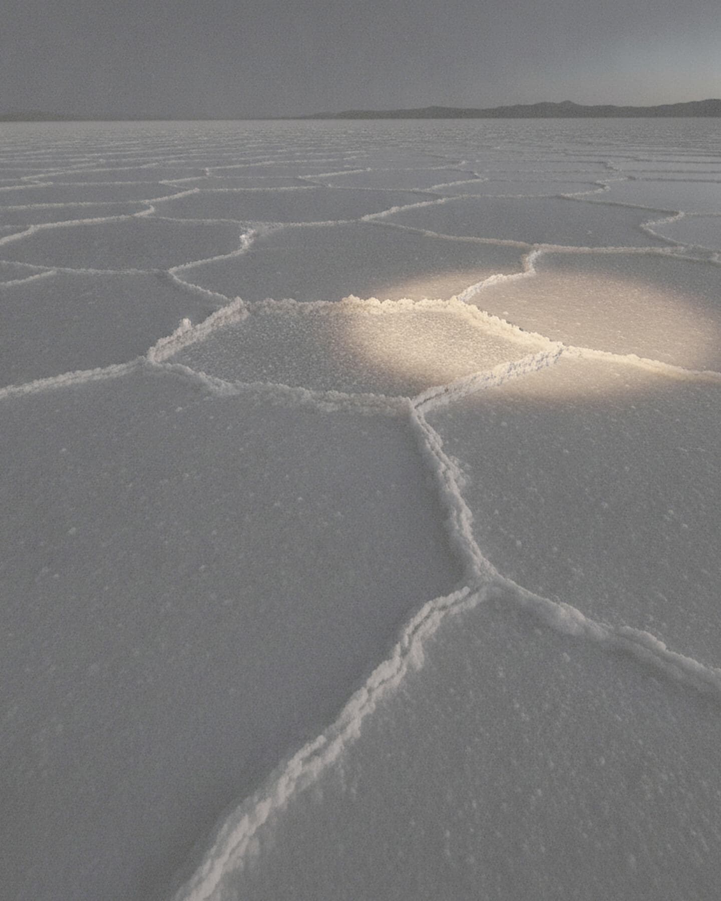 Weite Salzfläche im hellen Tageslicht, bis zum Horizont von Salzrändern durchzogen